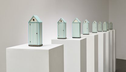 Models of Cabina dell'Elba – beach hut-inspired wardrobes – by Aldo Rossi on plinths in gallery